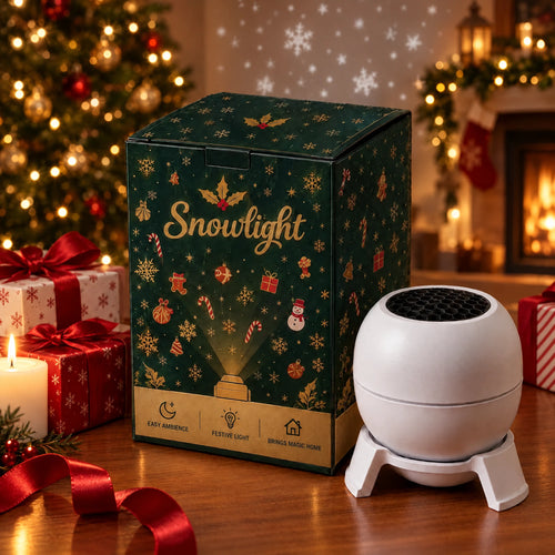 Snowlight Christmas Sky Projector next to its gift box by the Christmas tree